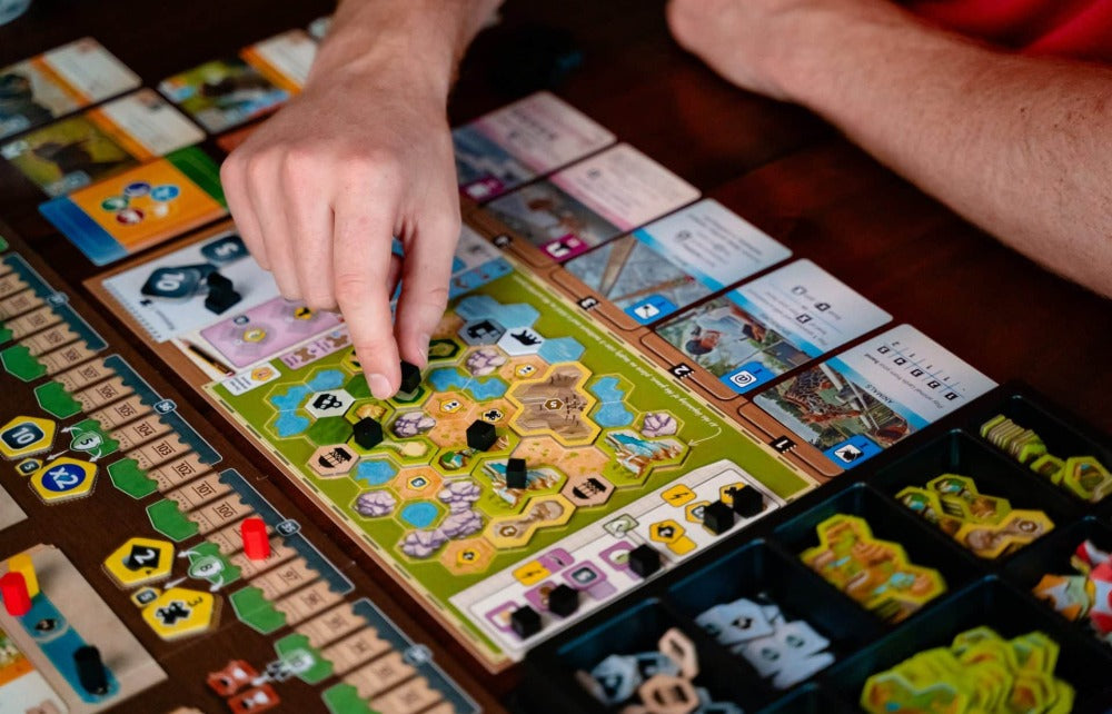 Components close-up — tokens, money, and the five-slot action card row that drives every turn.