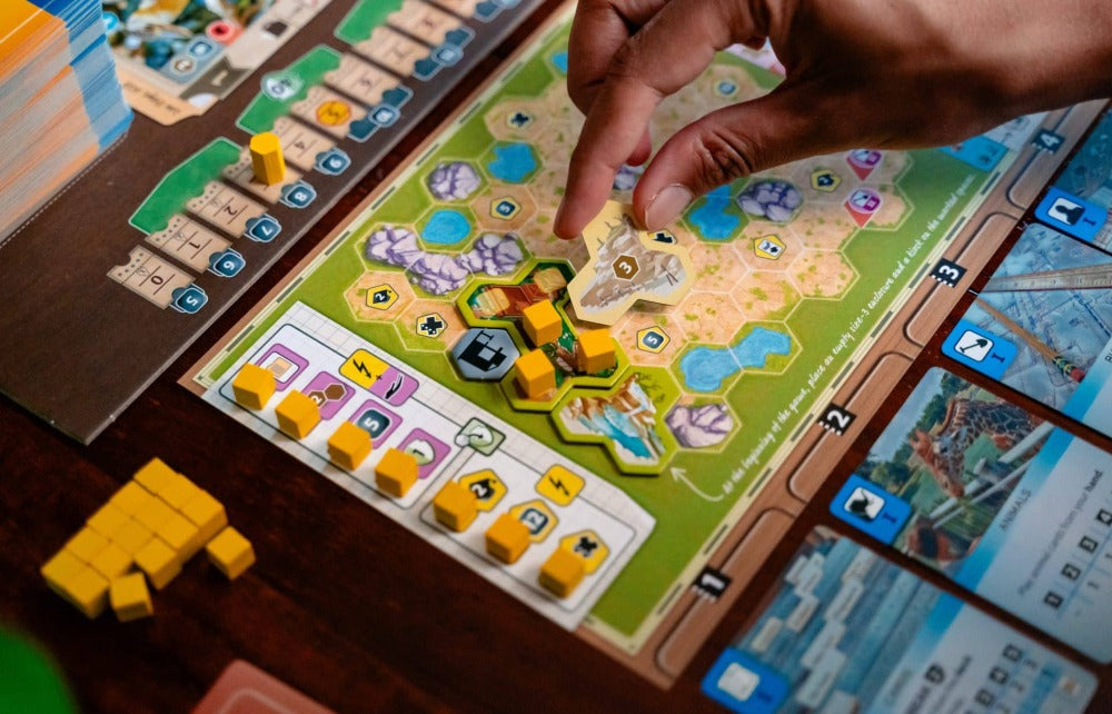 An expanding zoo board mid-build, dense with enclosures, animals, and scoring tracks.